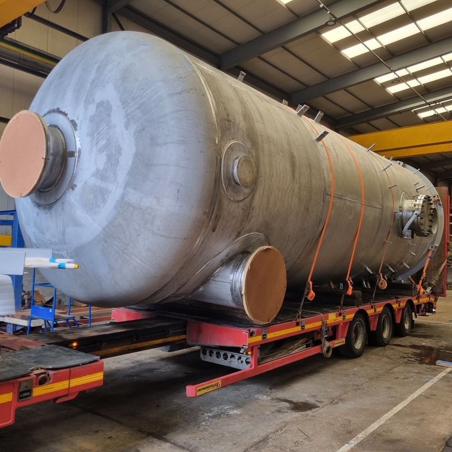 A large-bore pressure vessel leaves the shop floor, loaded for transport to site.